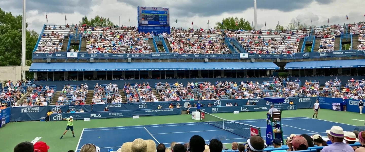 Tennis match in progress at the Citi Open with a crowd of spectators in the stands at the venue in Washington, DC.