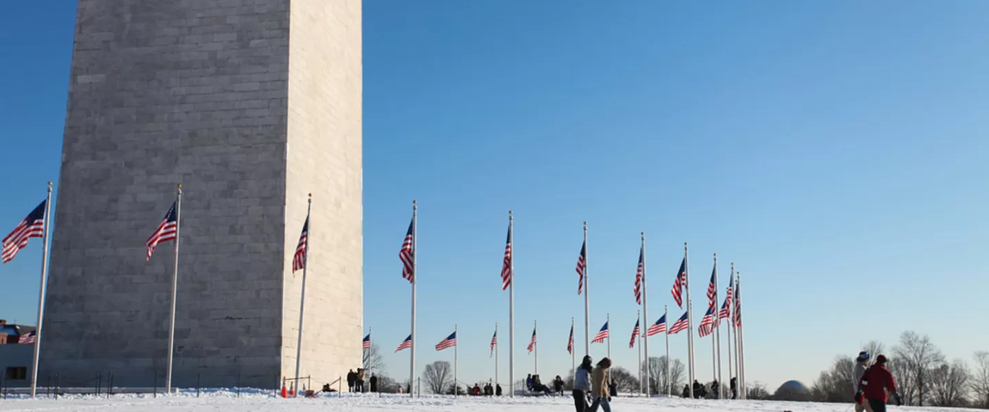 Family on snowy Washington Monument grounds on the National Mall - The best snow day activities in Washington, DC