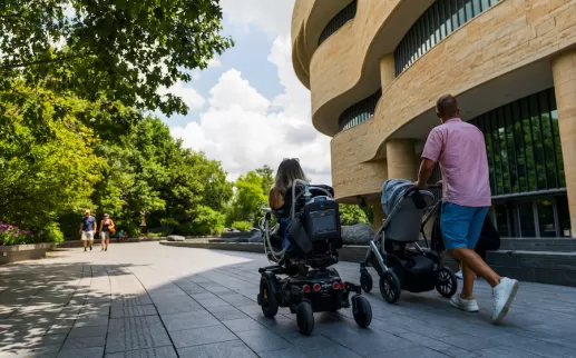 A family outside a museum, one pushing a stroller and another in a wheelchair