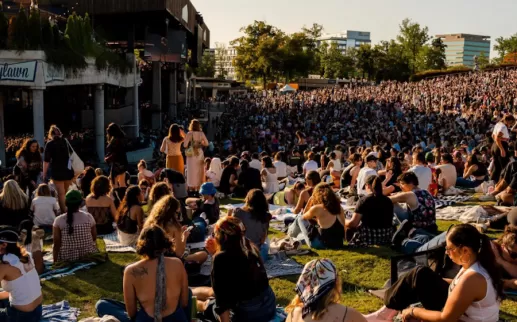 concertgoers seated on the lawn in front of a pavilion
