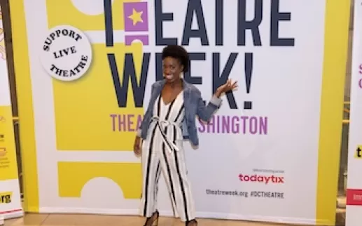 Woman posing in front of a Theatre Week banner.
