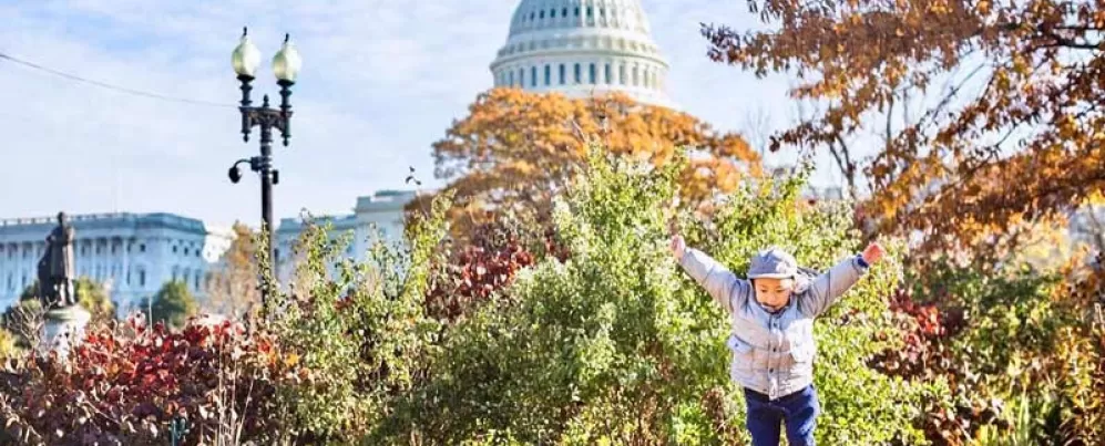 @chasingkaiphoto - Child jumping in front of the U.S. Capitol building surrounded by fall foliage - Fall in Washington, DC